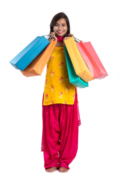 Belle jeune fille indienne tenant et posant avec des sacs à provisions sur un blanc