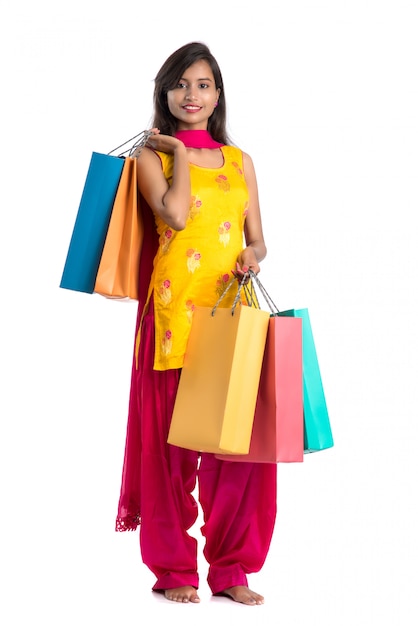 Belle jeune fille indienne tenant et posant avec des sacs à provisions sur fond blanc