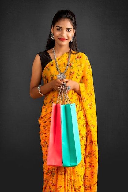 Belle jeune fille indienne tenant et posant avec des sacs à provisions sur fond gris