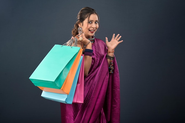 Belle jeune fille indienne tenant et posant avec des sacs à provisions sur fond gris