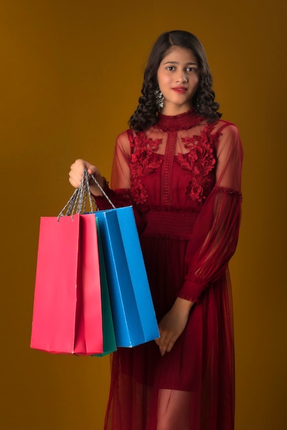 Belle jeune fille indienne tenant et posant avec des sacs à provisions sur fond marron