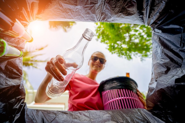 Une belle jeune fille jette des ordures triées dans des poubelles spéciales