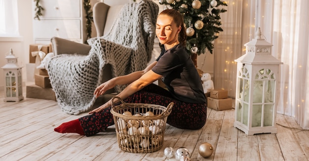 Belle jeune fille joyeuse et heureuse sur le sol en pyjama avec des jouets de noël près de l'arbre du nouvel an à la maison