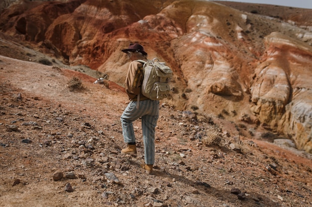 Photo belle jeune fille en lièvre, chapeau et sac à dos va parmi les sables à l'état sauvage