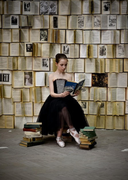 Une belle jeune fille lit un livre dans le contexte d'un mur avec des livres