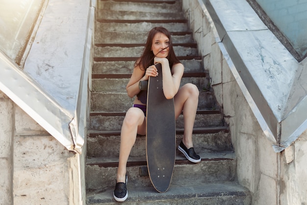 Belle jeune fille avec une longue planche dans la ville.