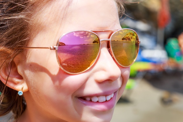 Belle jeune fille à lunettes de soleil avec reflet de parasol