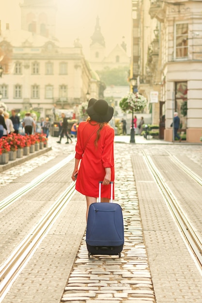 Belle jeune fille marchant avec une valise bleue.