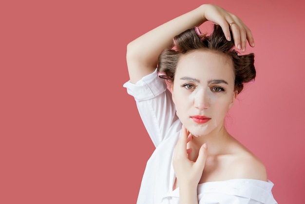 Belle Jeune Fille Avec Un Masque Et Des Bigoudis Touchant Son Visage