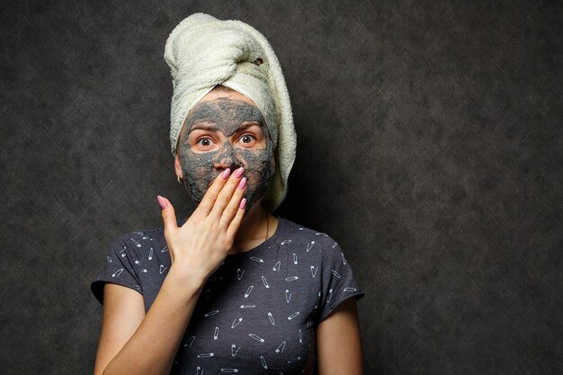 Belle jeune fille avec un masque en mousse tonique sur le visage et une serviette attachée avec des cheveux