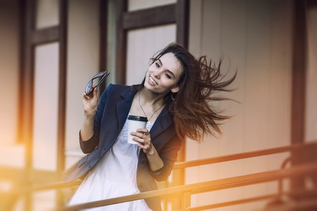 Belle jeune fille de la mode vient d'un café avec du café à emporter à la main