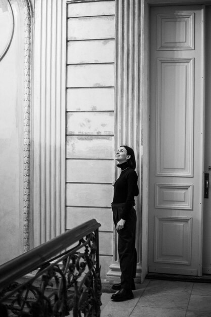 Photo belle jeune fille en noir debout à l'intérieur