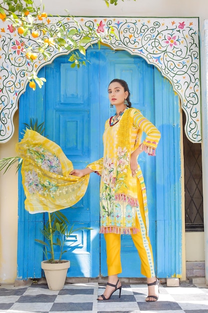 Belle jeune fille pakistanaise agitant Dupatta vêtue d'une robe Desi jaune pour une séance photo en plein air