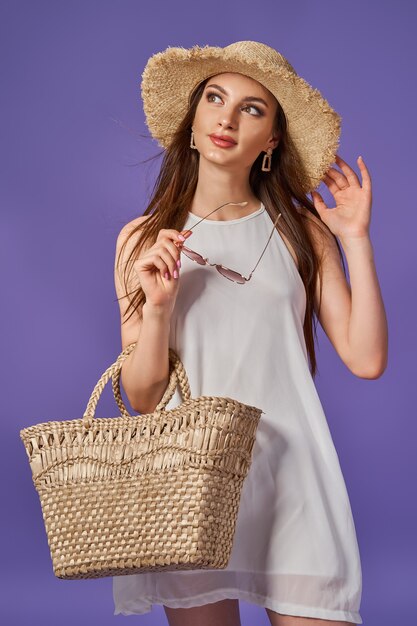 belle jeune fille portant une robe avec des chapeaux de paille qui pose en studio