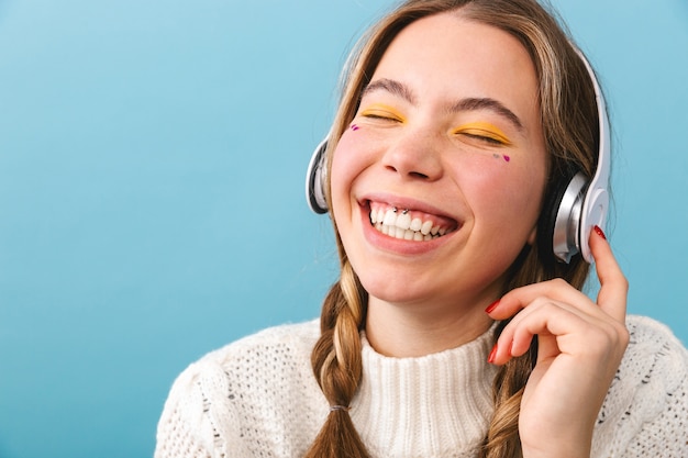 Belle jeune fille portant des vêtements d'hiver isolés, écoutant de la musique avec des écouteurs