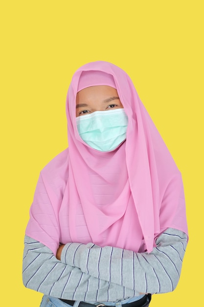 Belle jeune fille porte un hijab rose et un masque sur fond jaune
