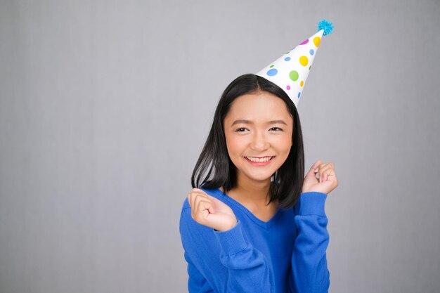 Belle jeune fille porte un pull bleu et un chapeau de fête sur fond blanc