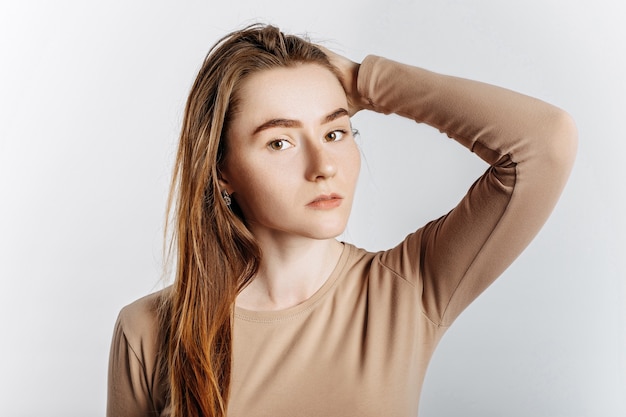 Belle jeune fille posant en regardant la caméra sur un fond blanc isolé.