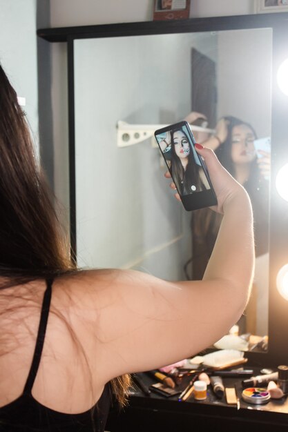 Photo belle jeune fille prenant un selfie de son maquillage d'halloween dans sa chambre - image verticale.