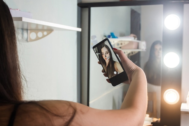 Belle jeune fille prenant un selfie de son maquillage d'Halloween dans sa chambre.