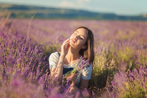 Belle jeune fille profitant du soleil dans un champ de lavande