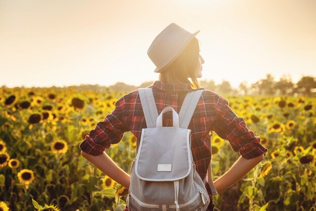 Belle jeune fille, profitant de la nature sur le champ de tournesols au coucher du soleil