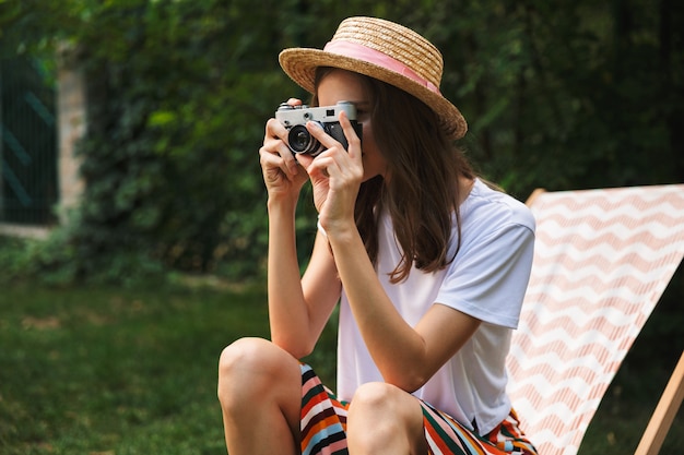 Belle jeune fille reposant sur un hamac dans le parc de la ville à l'extérieur en été, prenant une photo avec appareil photo