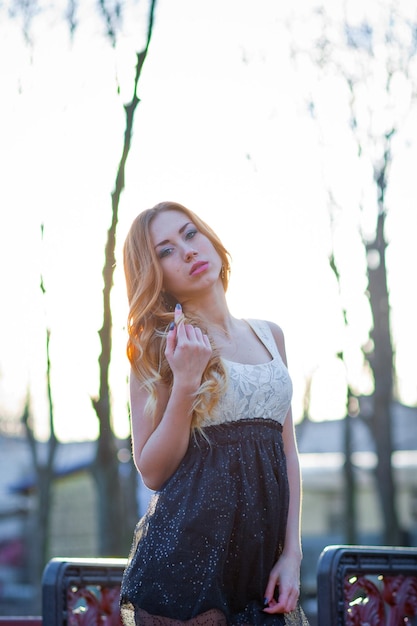 Belle jeune fille rousse vêtue d'une robe dans le parc. Belle jeune fille aux longs cheveux bouclés rouges