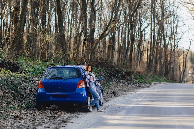 Belle jeune fille sur la route près de la voiture