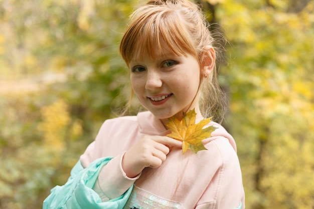 Belle jeune fille s'amusant avec des feuilles dans un parc en automne