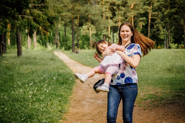 belle et jeune fille avec sa petite fille pour une promenade en jouant dans un parc en plein air près d'une forêt