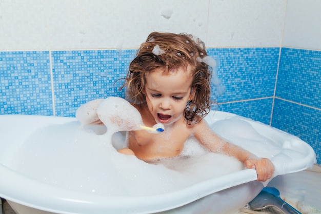 Belle jeune fille se baigne dans la salle de bain et se brosse les dents avec une brosse à dents.