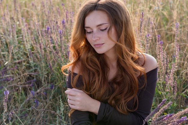 belle jeune fille se promène et cueille des fleurs dans le champ