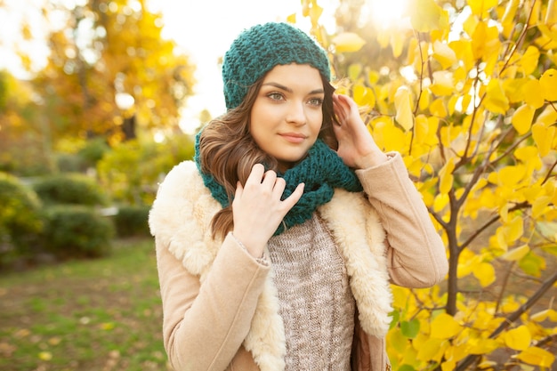 Une belle jeune fille se promène dans le parc en automne sur le fond de feuilles aux couleurs vives