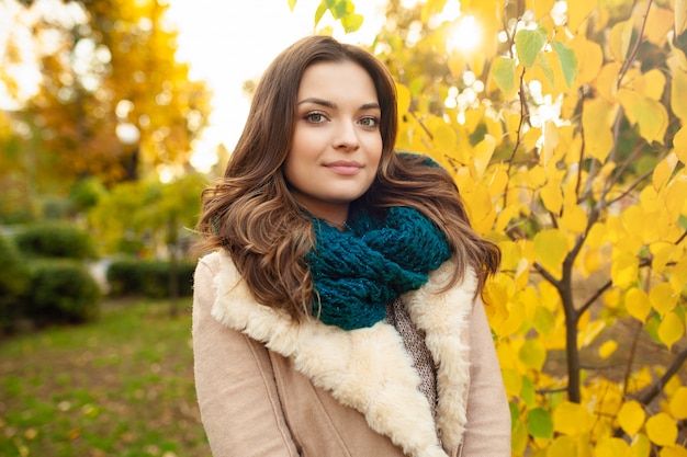 Une belle jeune fille se promène dans le parc en automne sur le fond de feuilles aux couleurs vives