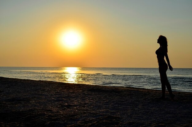 Photo une belle jeune fille se promène le long du rivage de sable le long de l'eau