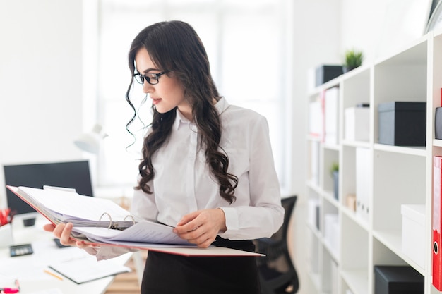 Belle jeune fille se trouve dans le bureau, un dossier avec des documents.