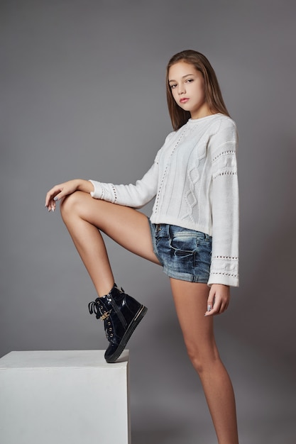 Belle jeune fille souriante assise sur un cube