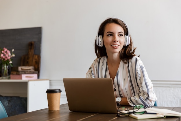 Belle jeune fille souriante assise à la table à la maison