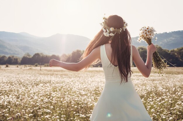 Belle jeune fille souriante sur le champ de camomille Femme brune heureuse et insouciante avec de longs cheveux sains s'amusant en plein air dans la nature