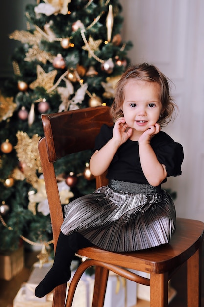 Belle jeune fille souriante jouant près de sapin de Noël à la maison