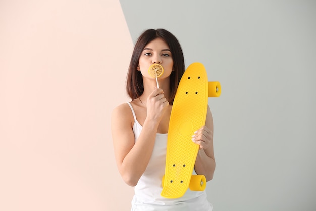 Belle jeune fille avec sucette et skateboard