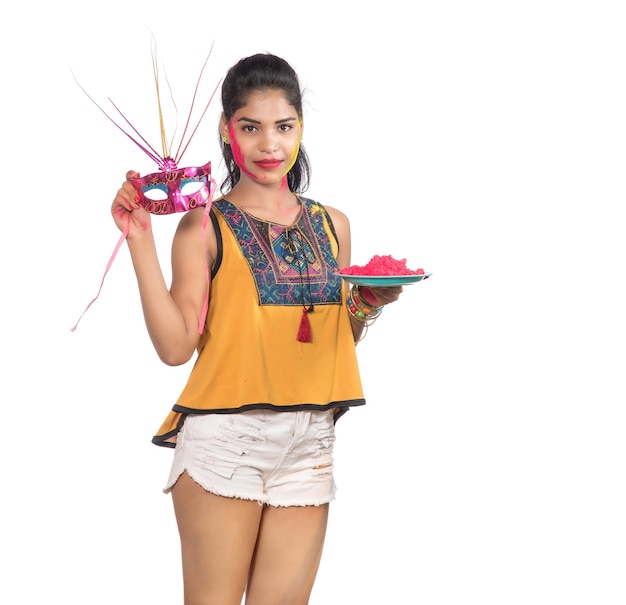 Belle jeune fille tenant la couleur en poudre dans la plaque avec masque de carnaval à l'occasion du festival de Holi.