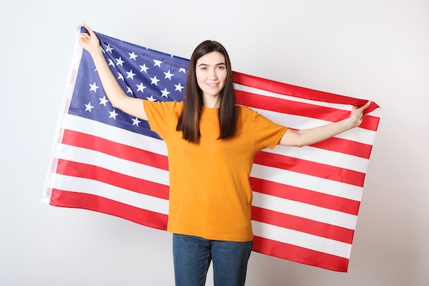 Belle jeune fille tenant le drapeau de l'Amérique sur un fond coloré