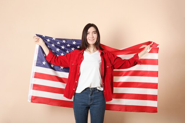 Belle jeune fille tenant le drapeau de l'Amérique sur un fond coloré