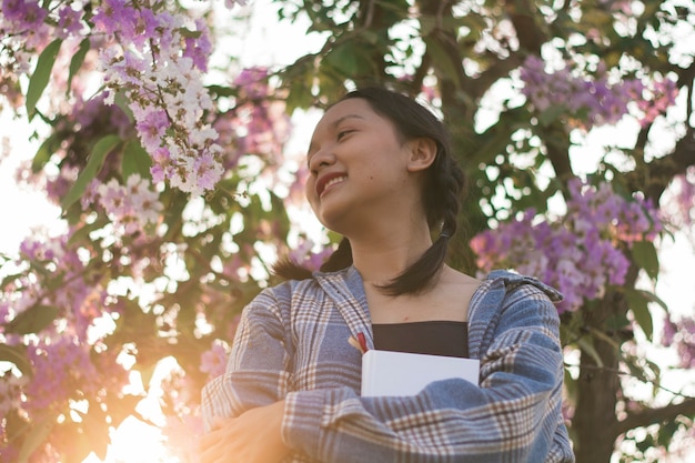 Belle jeune fille tient un livre blanc avec une fleur violette.