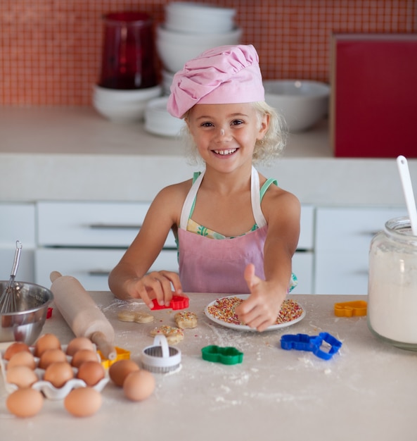 Belle jeune fille travaillant dans la cuisine pouce en haut