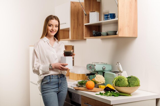 Une belle jeune fille végétarienne ou blogueuse prépare le petit-déjeuner de fruits légumes et légumes verts à la maison dans la cuisine Blog sur une alimentation saine