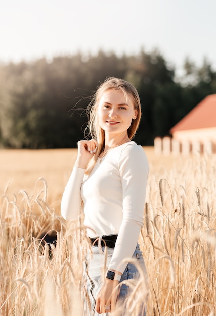 Une belle jeune fille vêtue d'une jupe en jean se promène dans un champ de blé par une journée ensoleillée