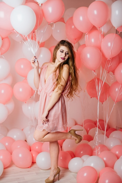 Belle jeune fille vêtue d'une robe parmi beaucoup de boules roses.